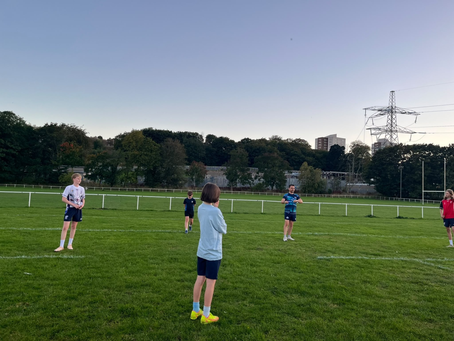 Adult supporting young players during a junior Touch session on a grass pitch